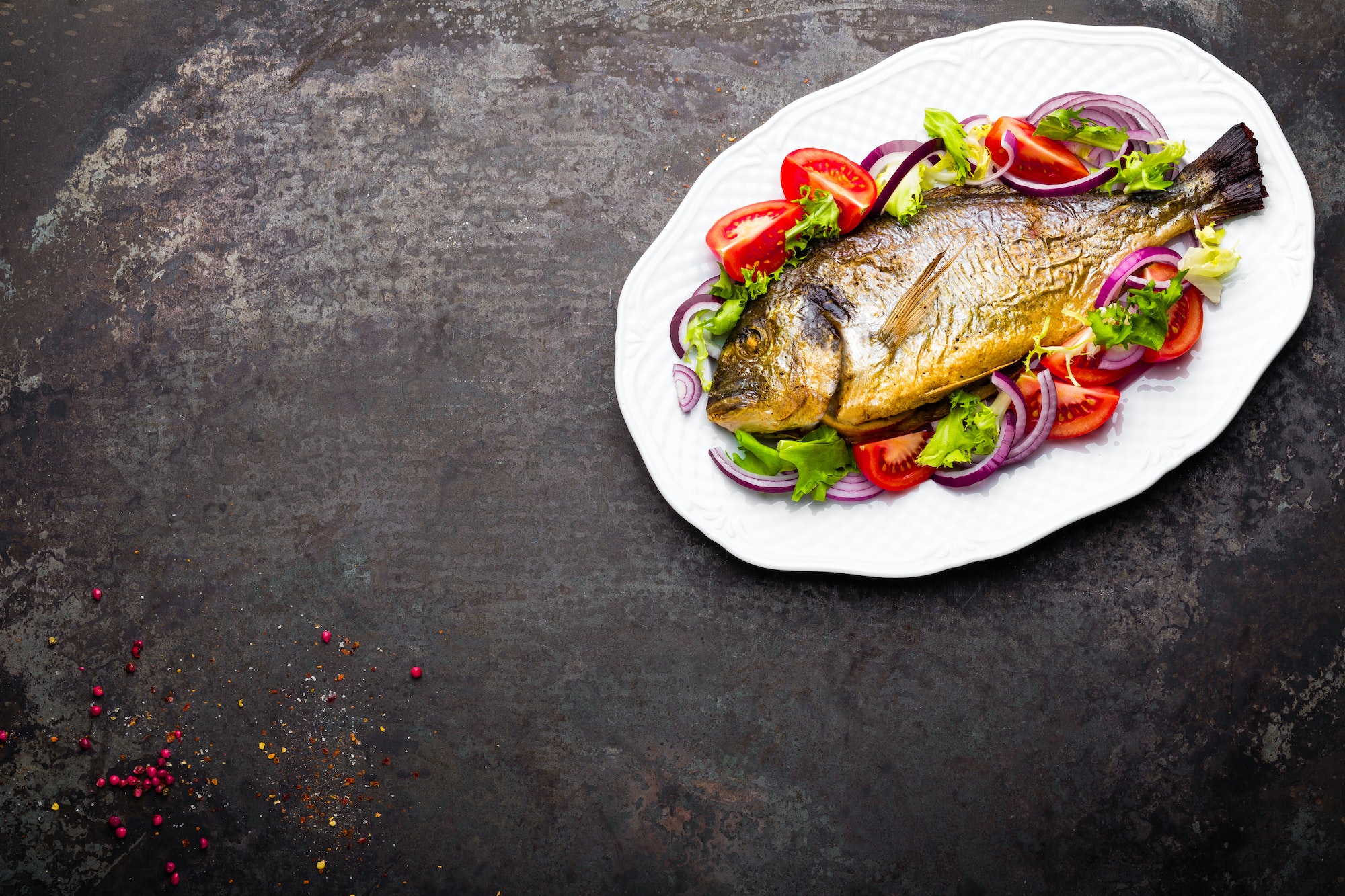 Baked fish dorado. Dorado fish oven baked and fresh vegetable salad on plate. Sea bream