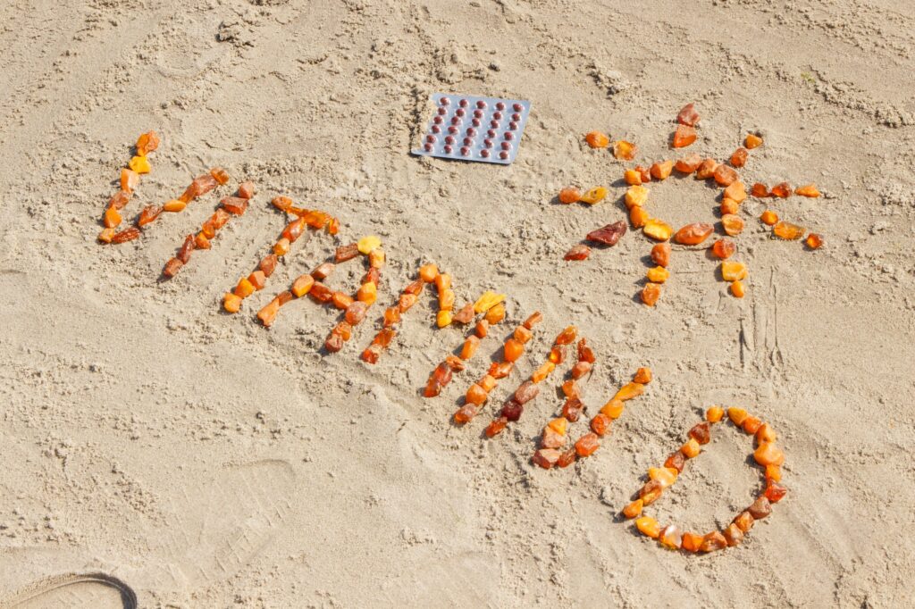 Medical pills, inscription vitamin D and shape of sun at beach